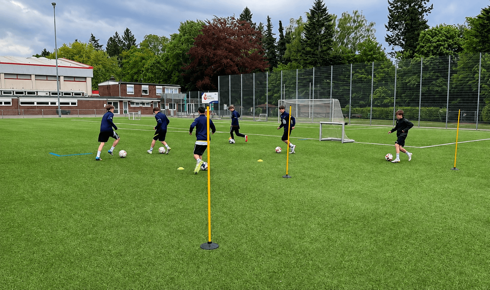 Kinder beim Techniktraining mit Stangen und Bällen im Stadion Reinbek.